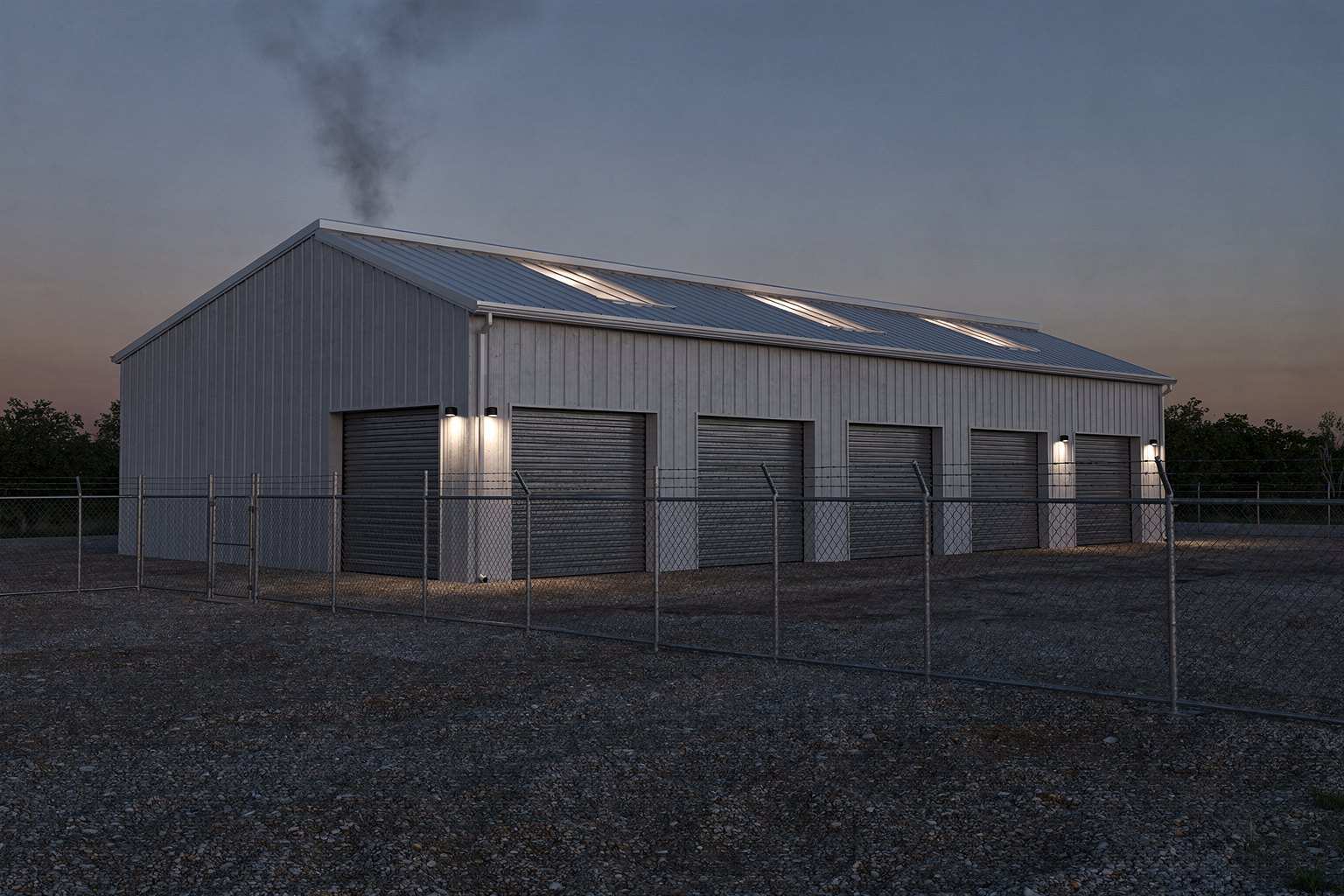 A generic one-story metal warehouse at dusk behind a chain-link fence, with closed roll-up doors, roof skylights and light smoke above the roof.